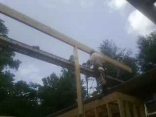 Carpenter setting a ridge beam over a new addition frame — Ice Dam Removal by Roofing Brothers in Grace