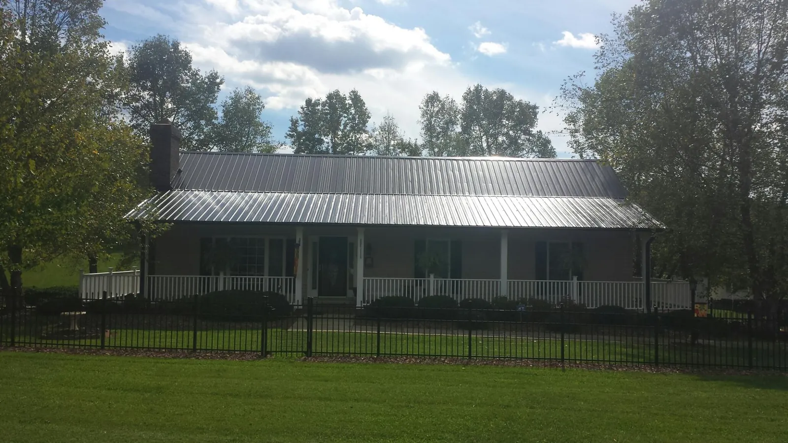 Gray metal roof on a brick ranch with a full width front porch — Gutter Guard Installation work by our crew in Grace
