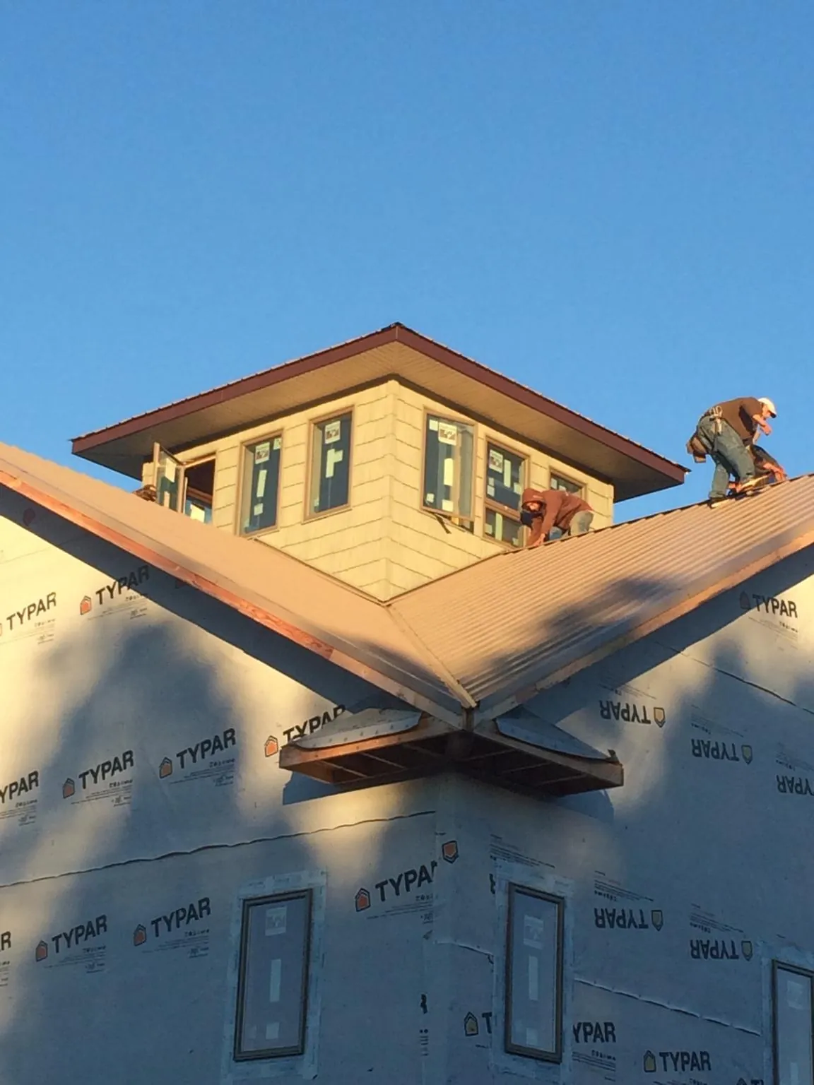 Roofers working around a rooftop cupola on a new metal roof at sunset — Roof Waterproofing in Grace by Roofing Brothers
